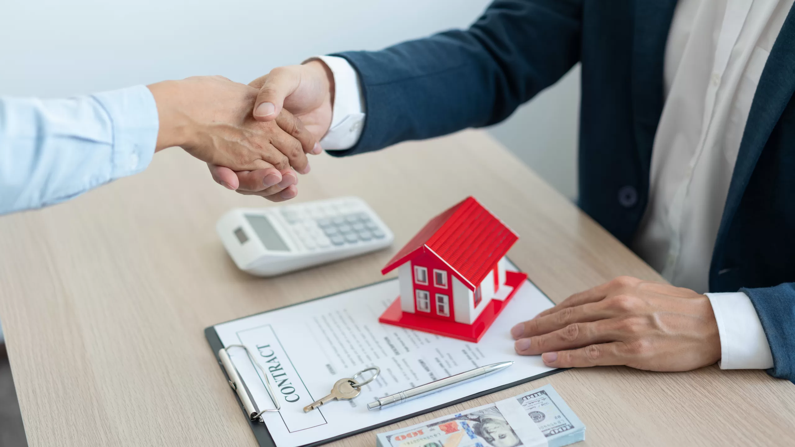 An estate agent and his client shaking hands for accepting the house sale contract.